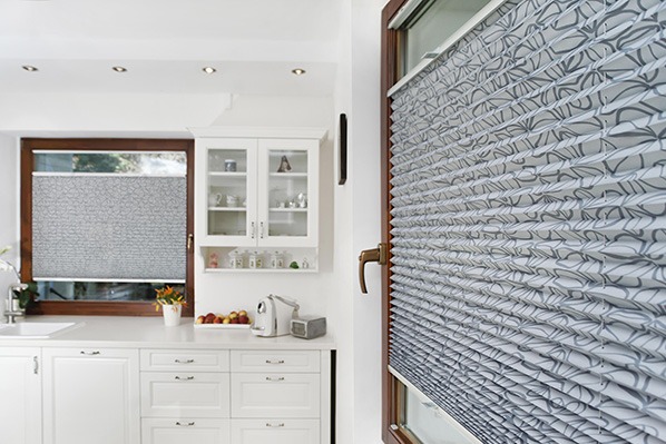 Szara, wzorzysta przesuwna osłona okienna w jasnej kuchni. Plisa zamontowana w oknie o drewnianej ramie, widok z bliska.