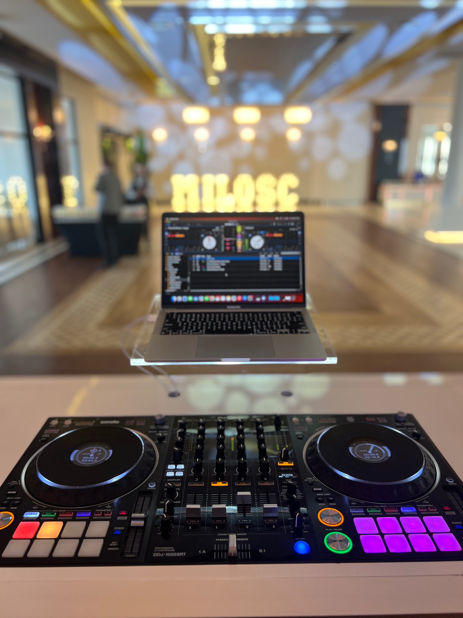 Sprzęt DJ: kontroler DDJ-1000SRT i laptop z oprogramowaniem na tle sali z dekoracją 'MIŁOŚĆ'. Gotowość do imprezy, eventu.