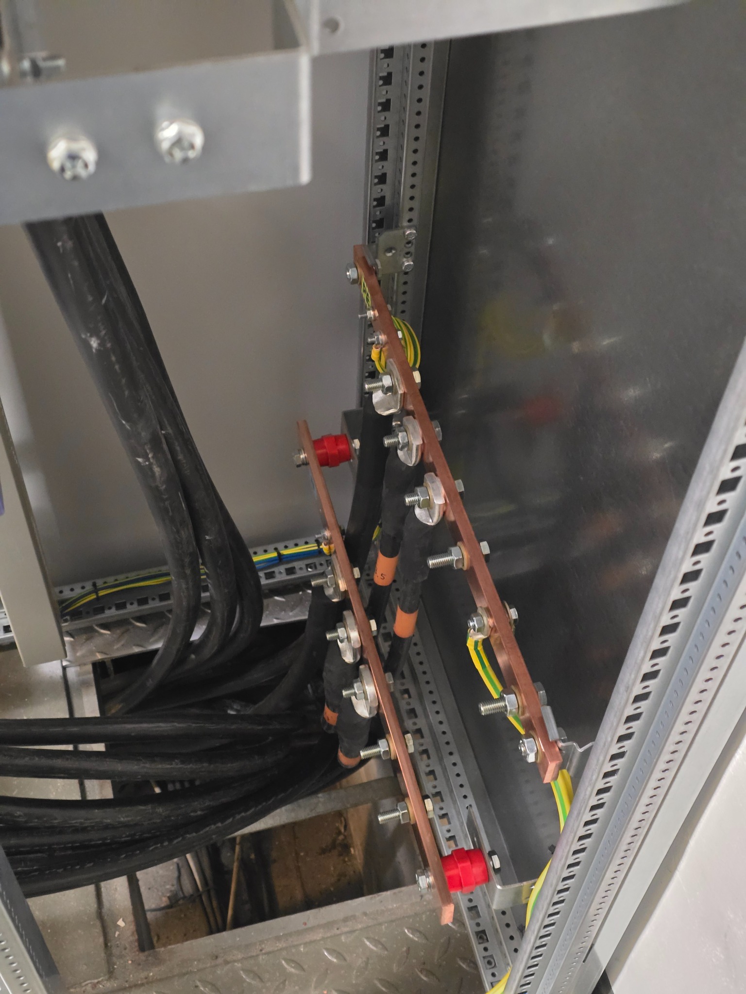 Wnętrze szafy elektrycznej z widocznymi kablami, szynami wyrównawczymi i elementami montażowymi. Detal instalacji elektrycznej w rozdzielnicy, kable w peszlach.