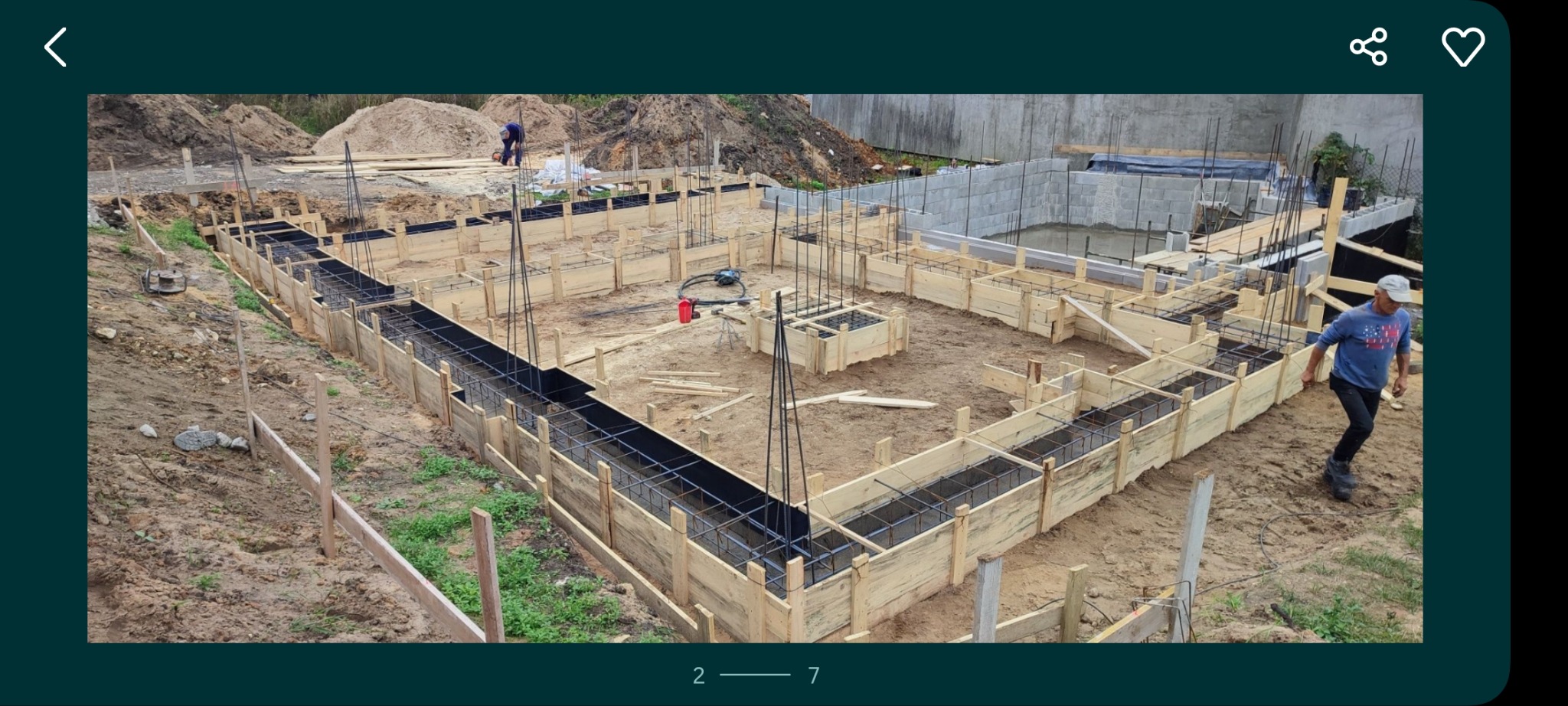 Zbrojenie i szalunek fundamentów pod budowę domu w Gliwicach. Widoczne drewniane formy i stalowe pręty. W tle wzniesione ściany z bloczków betonowych.