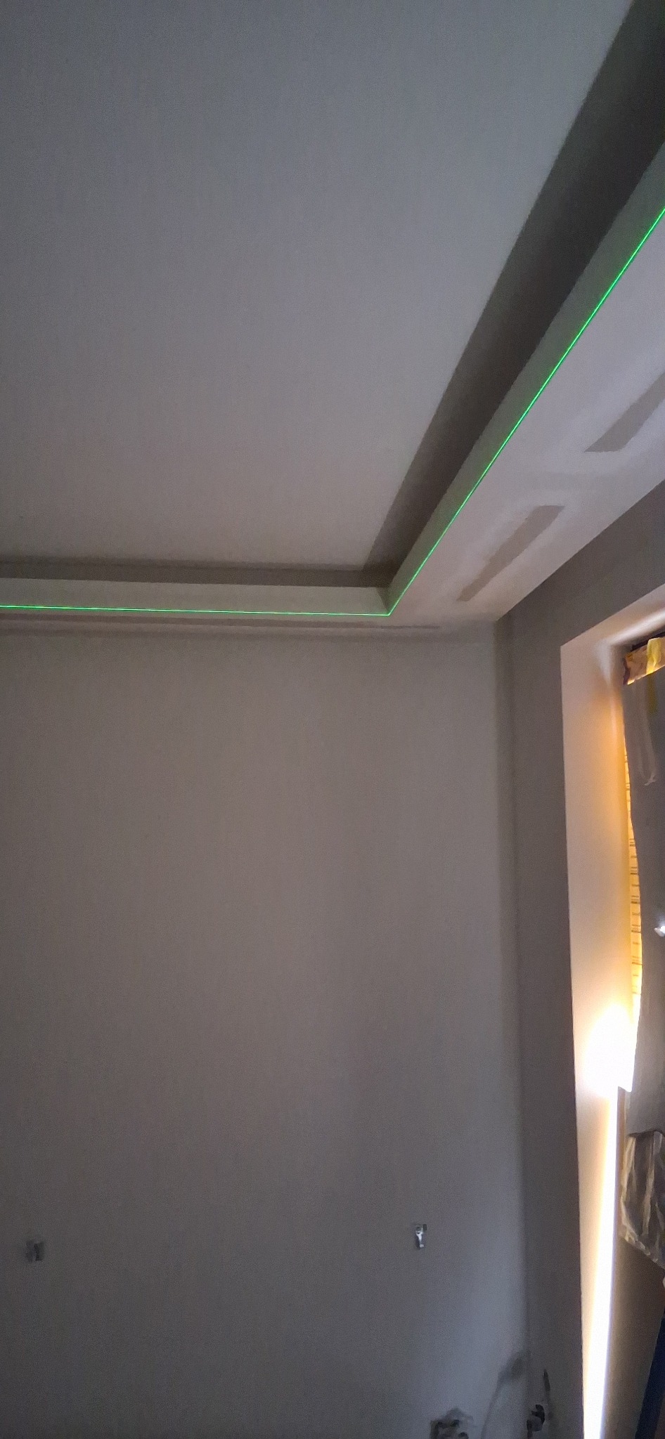 Wykończony sufit podwieszany z oświetleniem LED w świeżo pomalowanym pokoju. Widoczny laser poziomujący.