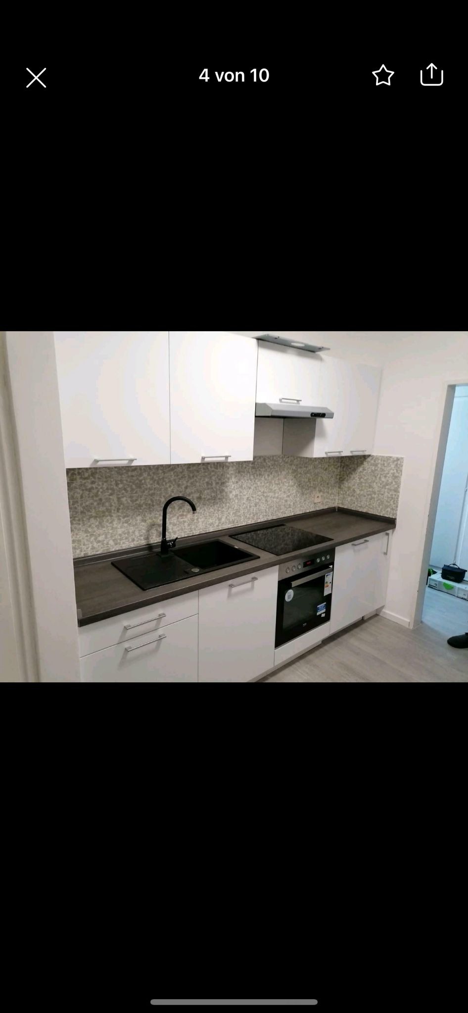 Biała kuchnia na wymiar z czarnym zlewem i płytą indukcyjną w Jeleniej Górze. Jasne szafki górne i mozaika na ścianie dodają elegancji.