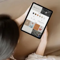 Kobieta trzyma tablet z projektem identyfikacji wizualnej marki osobistej z paletą kolorów, fontami i moodboardem, prezentującym logo i zdjęcia.
