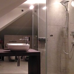Łazienka ze skosami i kabiną walk-in. Przeszklona kabina została zaprojektowana w narożniku, w najwyższej części pomieszczenia, co pozwoliło funkcjonalnie wykorzystać trudną przestrzeń pod skosami. Projekt pod klucz: Architekt Anna Buczny Piękne Wnętrza.
