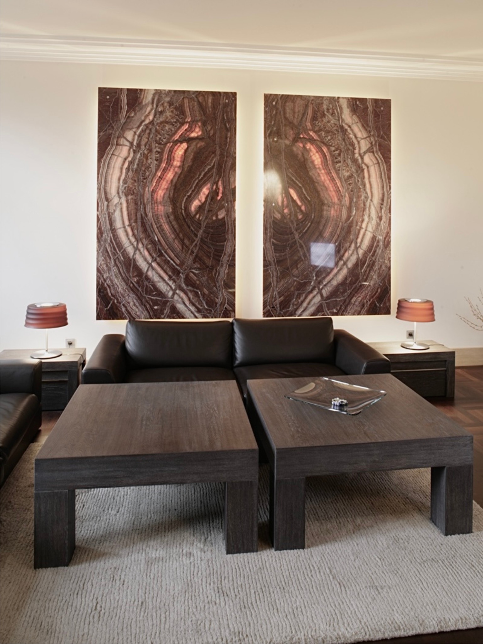 Salon w stylu vintage: ciemna sofa, stoliki kawowe z drewna, abstrakcyjne obrazy na ścianie z podświetleniem. Kamienica w centrum miasta, aranżacja wnętrza.