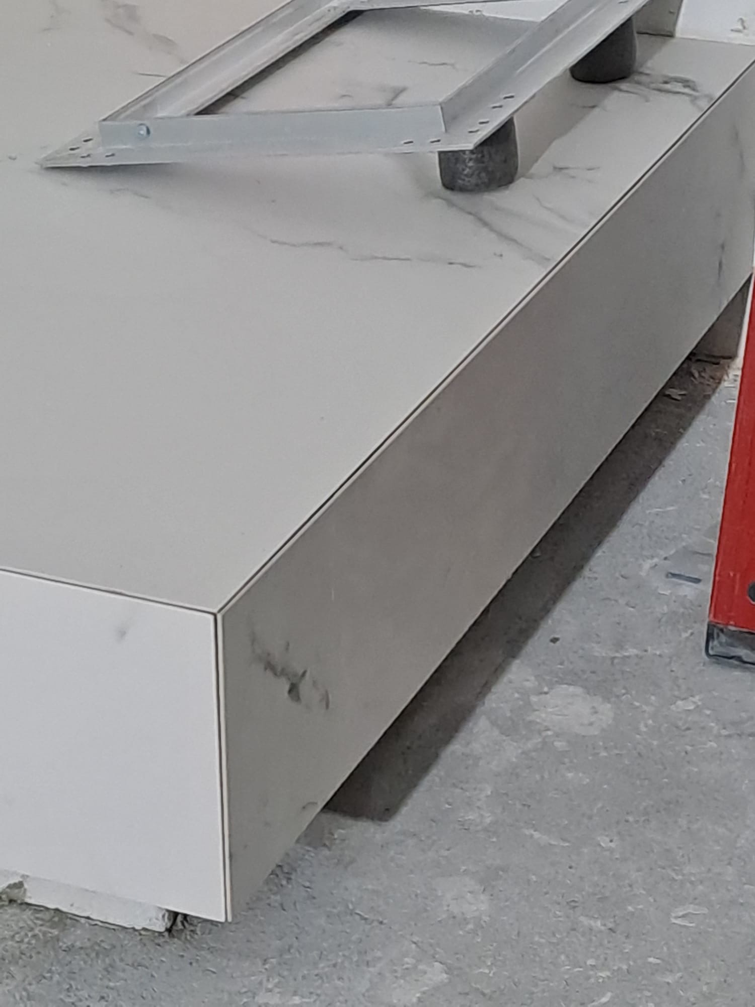 Wykończona obudowa wanny z płytek imitujących marmur, z widocznym stelażem i poziomnicą. Detal wykończenia łazienki, precyzyjne łączenie płytek.