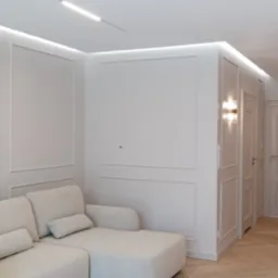 Eleganckie wykończenie wnętrza: kremowy narożnik, ściany z dekoracyjnymi listwami, parkiet w jodełkę i oświetlenie LED. Dwoje drzwi z ozdobnymi płycinami.