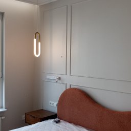 Daniel Zięba - Nowoczesna sypialnia w Damasławku: łóżko z pomarańczowym wezgłowiem, minimalistyczna lampa i stylowe panele ścienne. Wykończenie wnętrz.