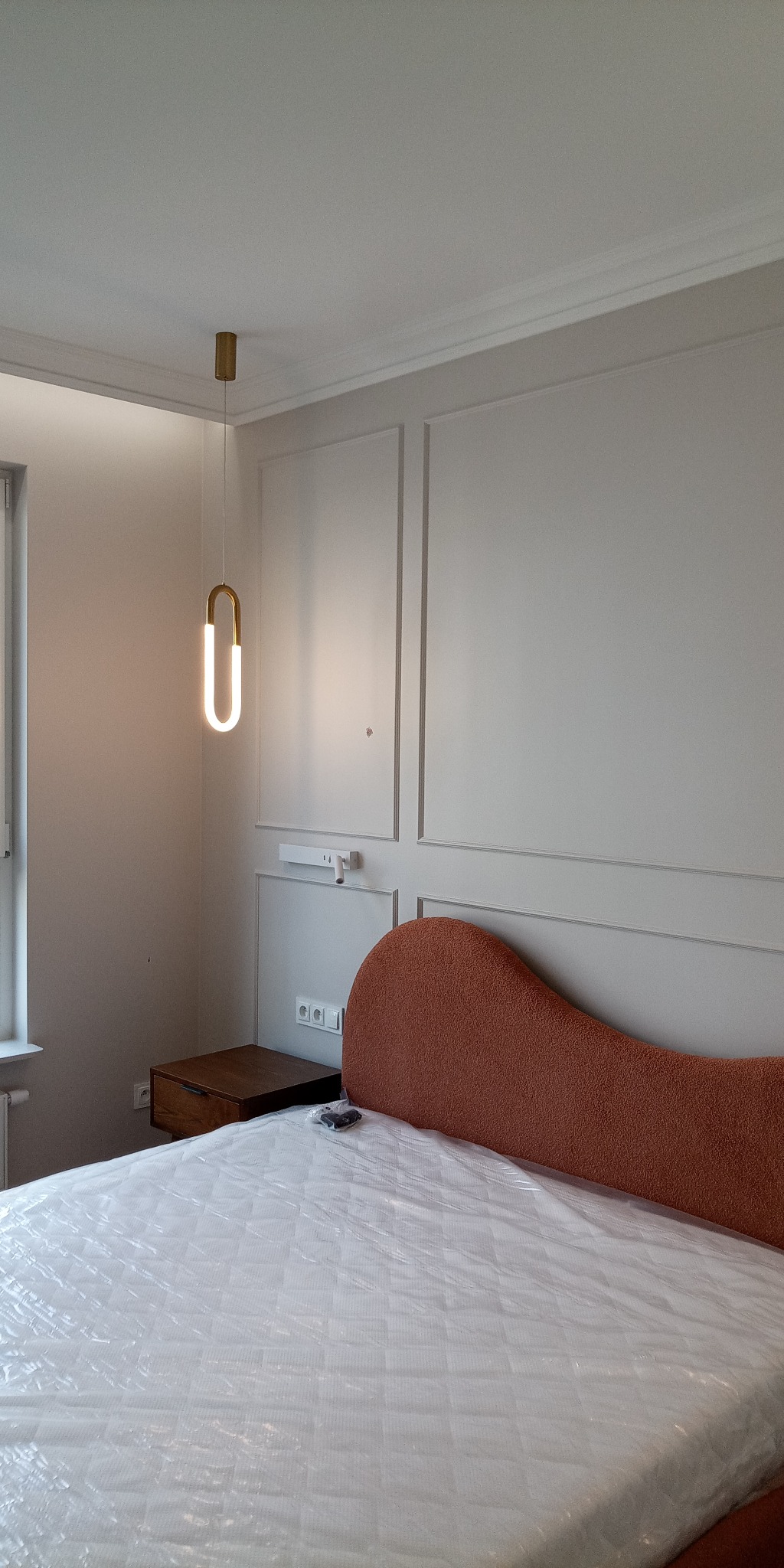 Nowoczesna sypialnia w Damasławku: łóżko z pomarańczowym wezgłowiem, minimalistyczna lampa i stylowe panele ścienne. Wykończenie wnętrz.