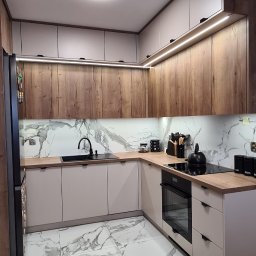 Inspiro-Meble Przemysław Wierzbicki - Nowoczesna kuchnia w kształcie litery L z drewnianymi i białymi szafkami, marmurowymi płytkami na podłodze i ścianie. Oświetlenie LED pod szafkami górnymi.