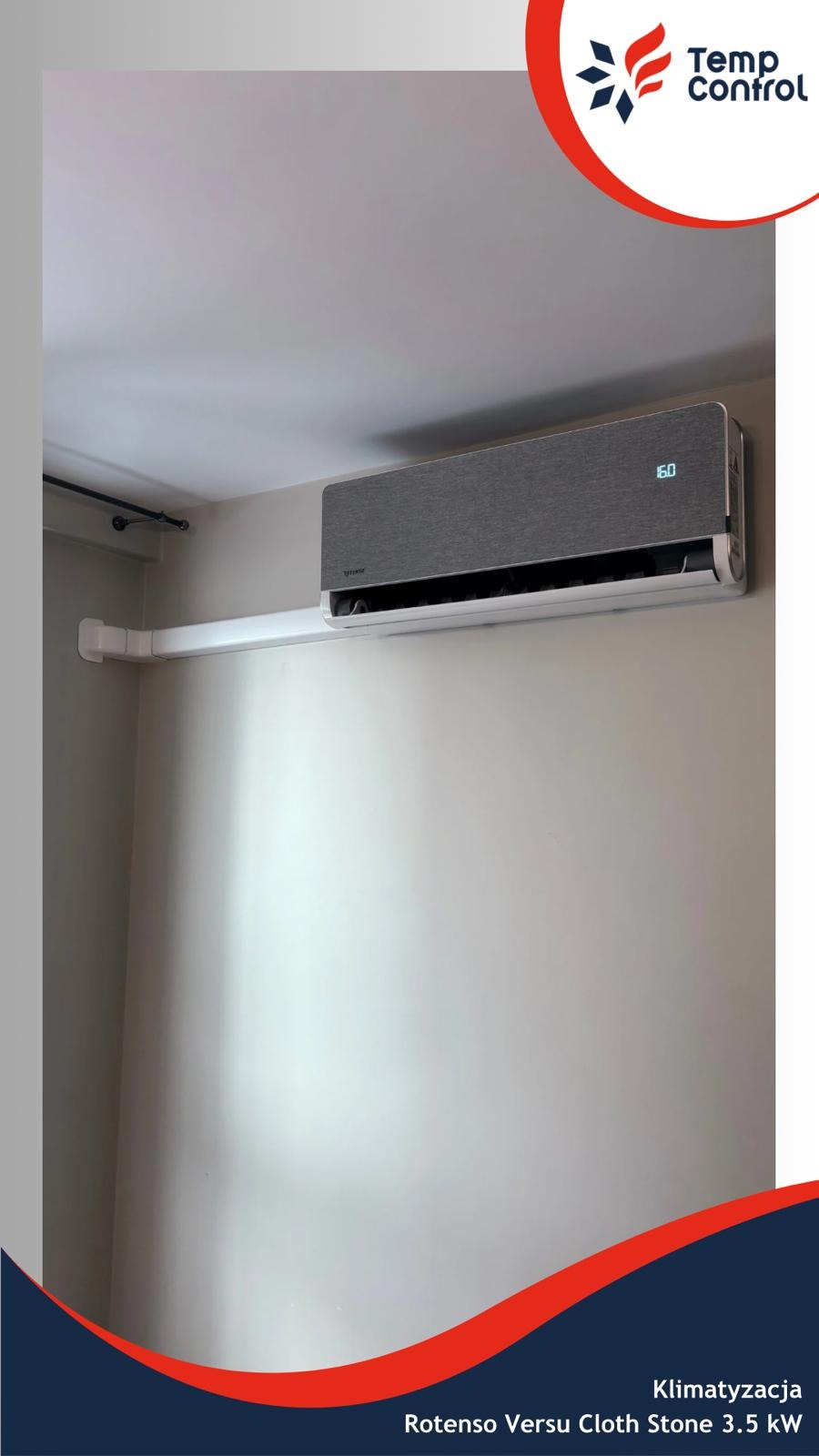 Szary klimatyzator Rotenso Versu Cloth Stone 3.5 kW, zamontowany na ścianie w pomieszczeniu. Widoczne białe rury odprowadzające skropliny i wyświetlacz z temperaturą 16 stopni.