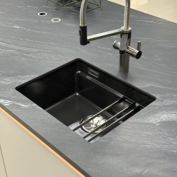 Zlewozmywak ceramiczny podwieszany w blacie ze spieku kwarcowego. Bateria z systemem filtrującym wodę oraz precyzyjnym dozownikiem