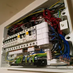 Otwarta skrzynka elektryczna z widocznymi przewodami i bezpiecznikami wewnątrz, instalacja wykonana w Warszawie. Widoczne złącza Wago.