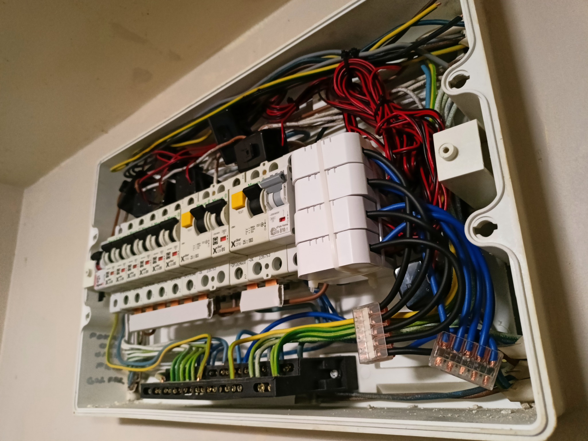 Otwarta skrzynka elektryczna z widocznymi przewodami i bezpiecznikami wewnątrz, instalacja wykonana w Warszawie. Widoczne złącza Wago.