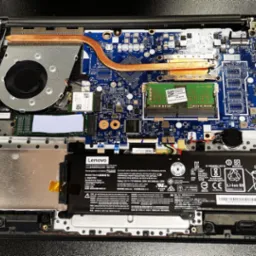 Wnętrze otwartego laptopa Lenovo z widoczną płytą główną, baterią, wentylatorem i elementami chłodzenia. Detaliczny widok na podzespoły komputera.