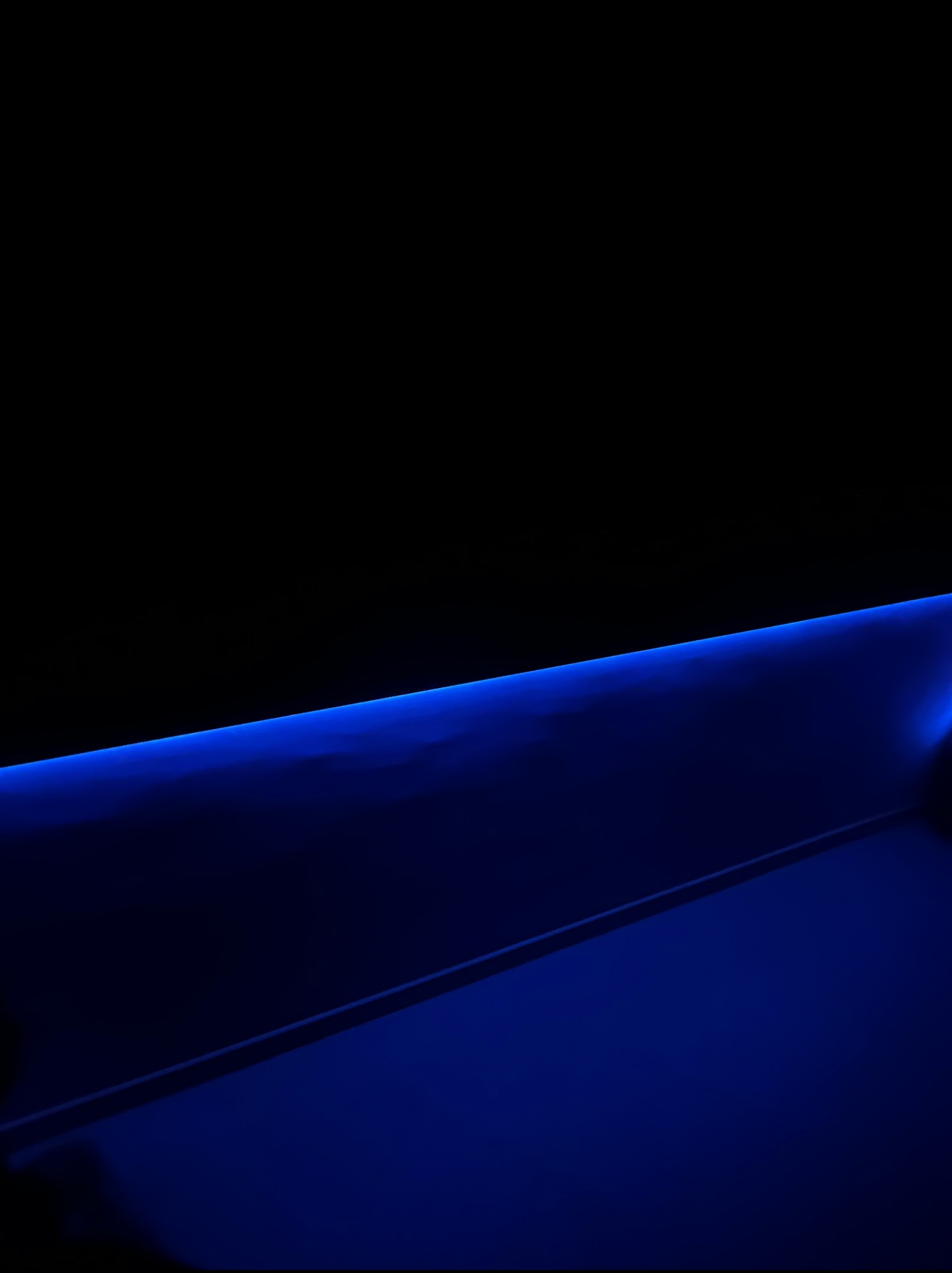 Nowoczesne oświetlenie LED w kolorze niebieskim, podkreślające architektoniczne detale wnętrza. Minimalistyczny design i subtelne światło tworzą futurystyczny efekt.