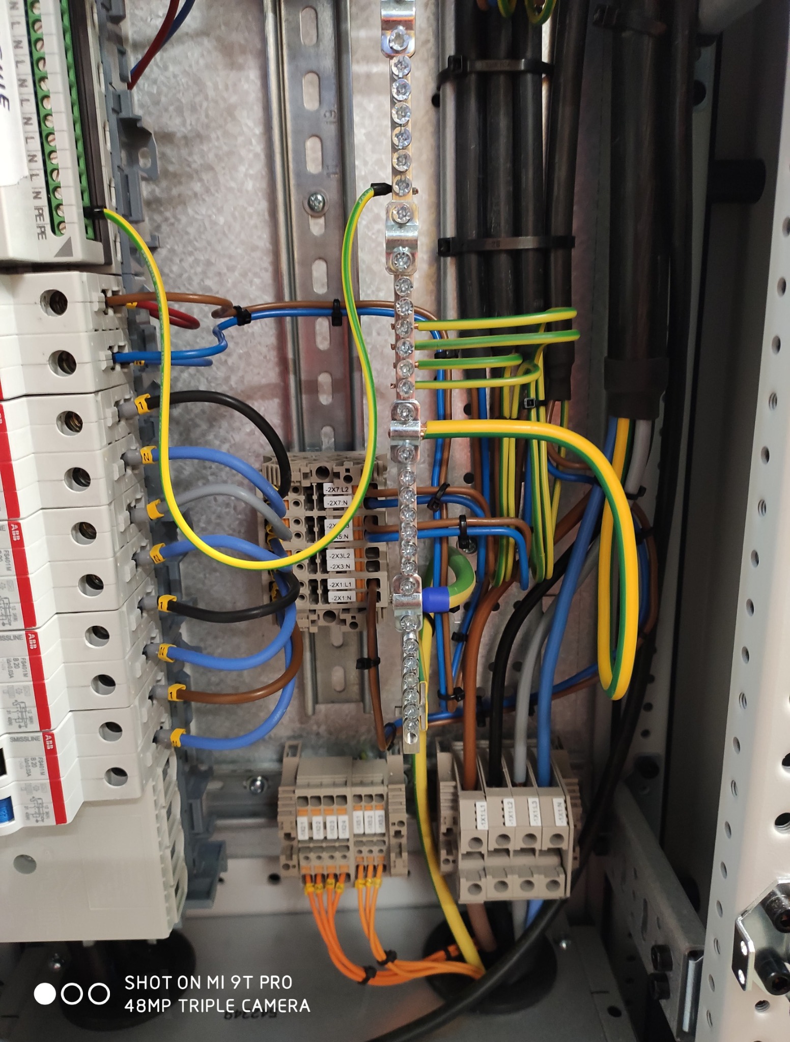 Szczegółowe ujęcie wnętrza szafy elektrycznej z widocznymi przewodami, złączkami i zabezpieczeniami. Elementy instalacji ułożone w uporządkowany sposób.