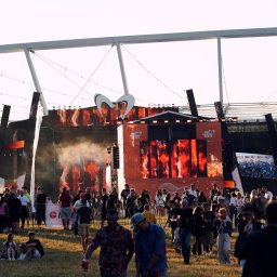 Nel Maczkiewicz - Widok na scenę z tłumem ludzi podczas festiwalu ING Silesia Beats, oświetloną pomarańczowym światłem, z widoczną konstrukcją dachu i logotypem imprezy.