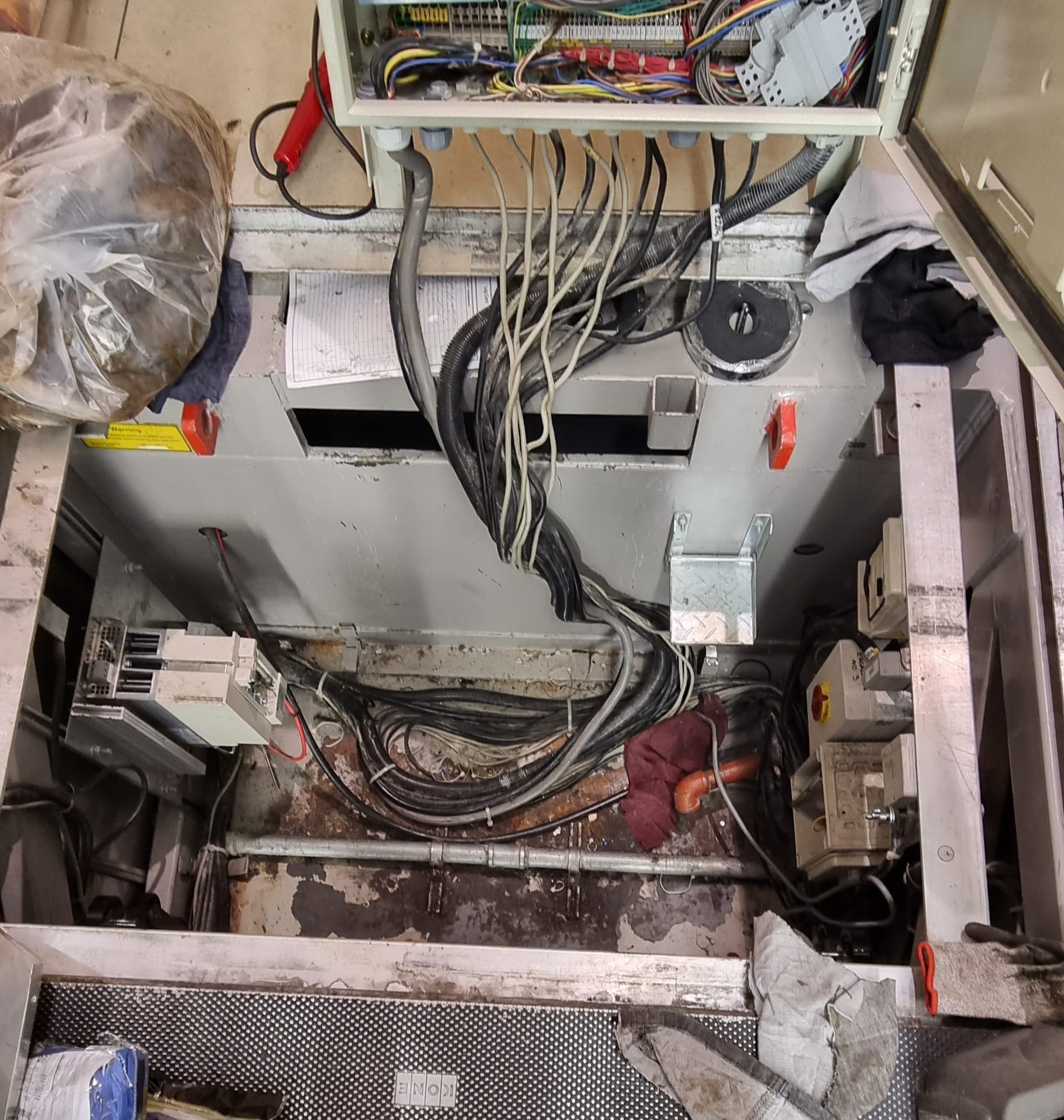 Otwarta skrzynka elektryczna z widocznymi kablami, elementami sterującymi i narzędziami. Widoczne ślady użytkowania, co sugeruje prace serwisowe lub naprawcze.