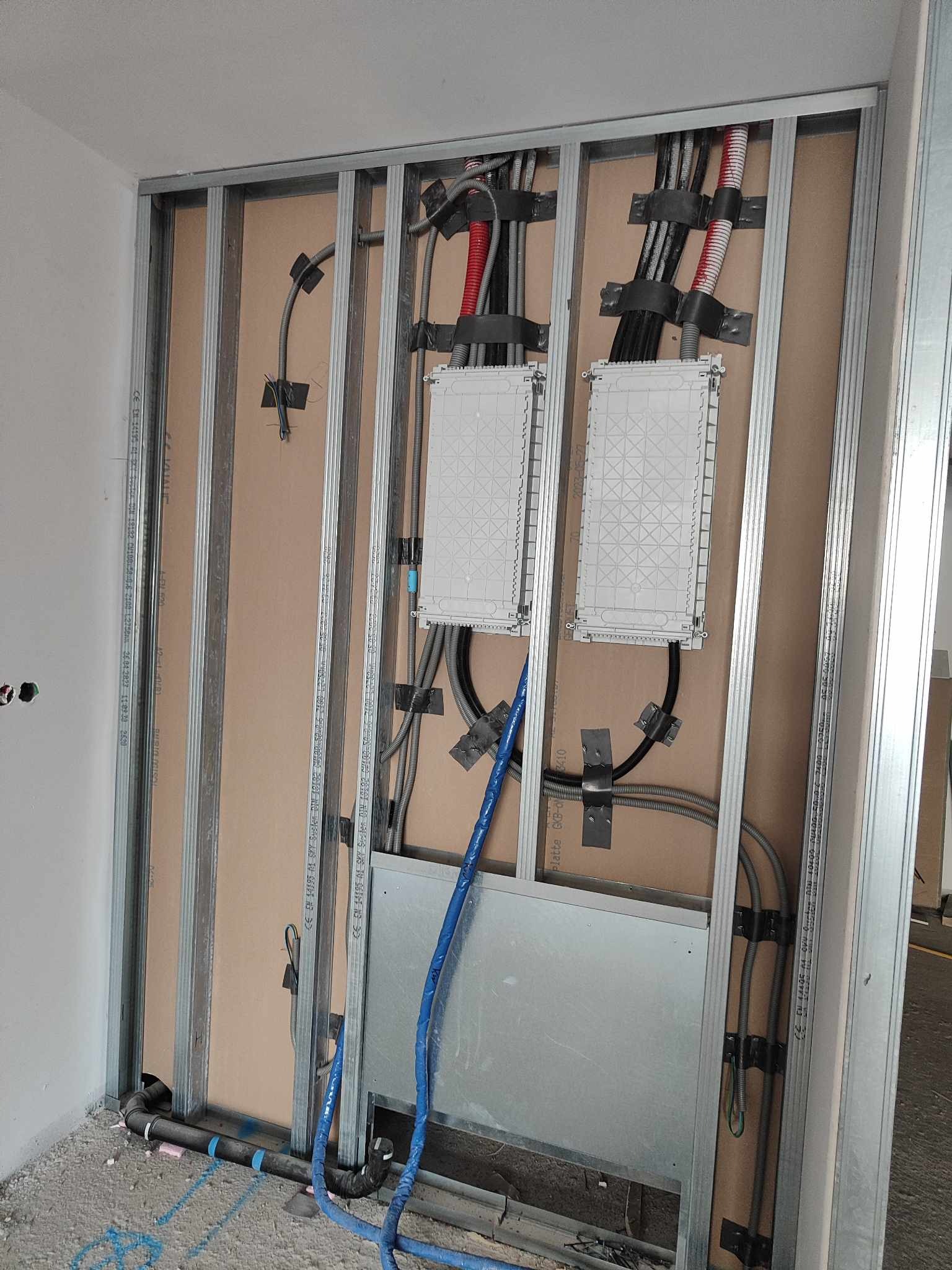 Konstrukcja metalowa z instalacjami: elektrycznymi (kable w peszlach), teletechnicznymi (światłowód) i kanalizacyjnymi. Widoczne puszki instalacyjne i rury odpływowe.