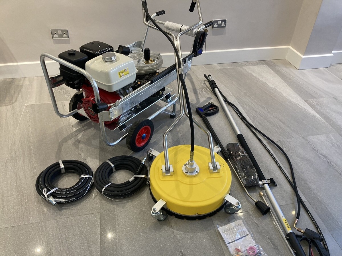 Profesjonalna myjka ciśnieniowa z akcesoriami: dysza rotacyjna, lanca teleskopowa i węże. Urządzenie gotowe do pracy, ustawione na płykach w pomieszczeniu.
