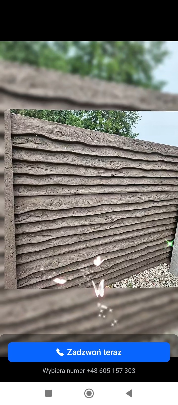 Panelowy, betonowy płot imitujący drewno, z widoczną fakturą i detalami słojów, w tle zieleń drzew. Ułożony obok żwir.