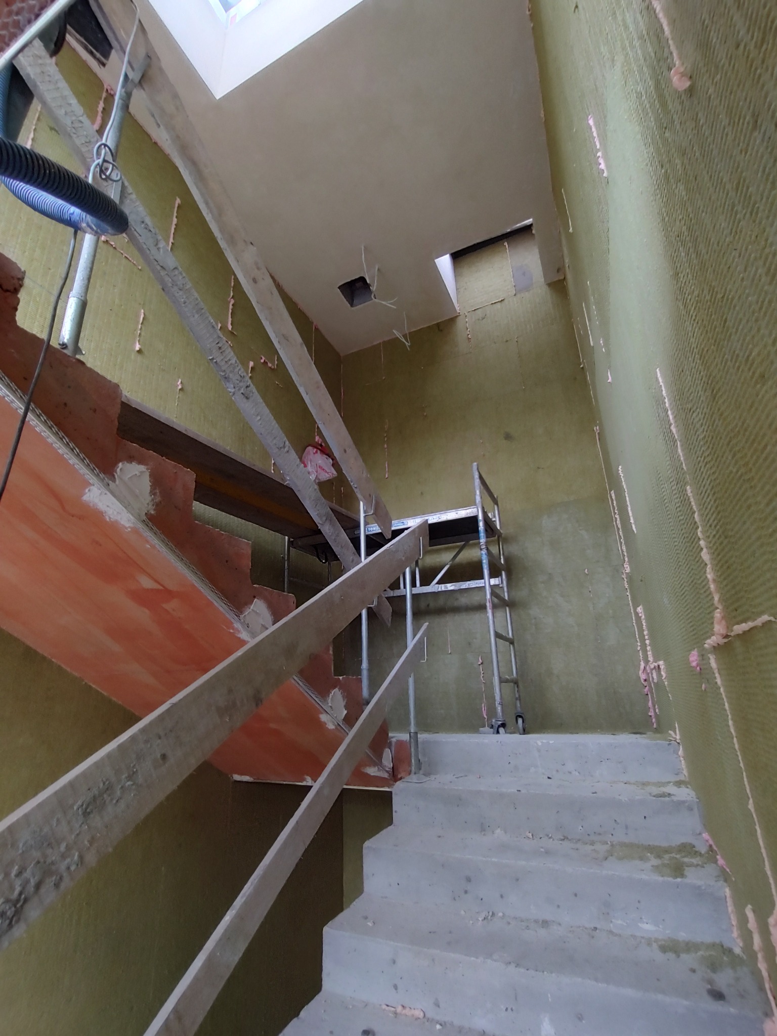 Izolacja ścian żelbetowych wełną mineralną grubości 3 cm korytarzu i klatki schodowej bloku mieszkalnego.