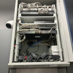 WOJCIECH BORMAN KOMPLEXSERWIS - Szafa rack z zamontowanym sprzętem sieciowym: routery, switche, patch panel. Widoczny kabel CCTV. Uporządkowane okablowanie. Montaż w szafie Q-LANTEC.