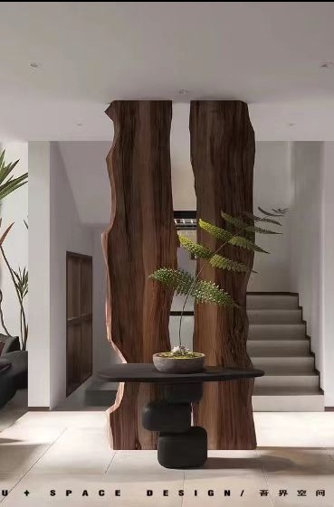 Nowoczesny hall z drewnianą ścianką działową o nieregularnych krawędziach i minimalistycznym stolikiem z rośliną w doniczce. Schody w tle.