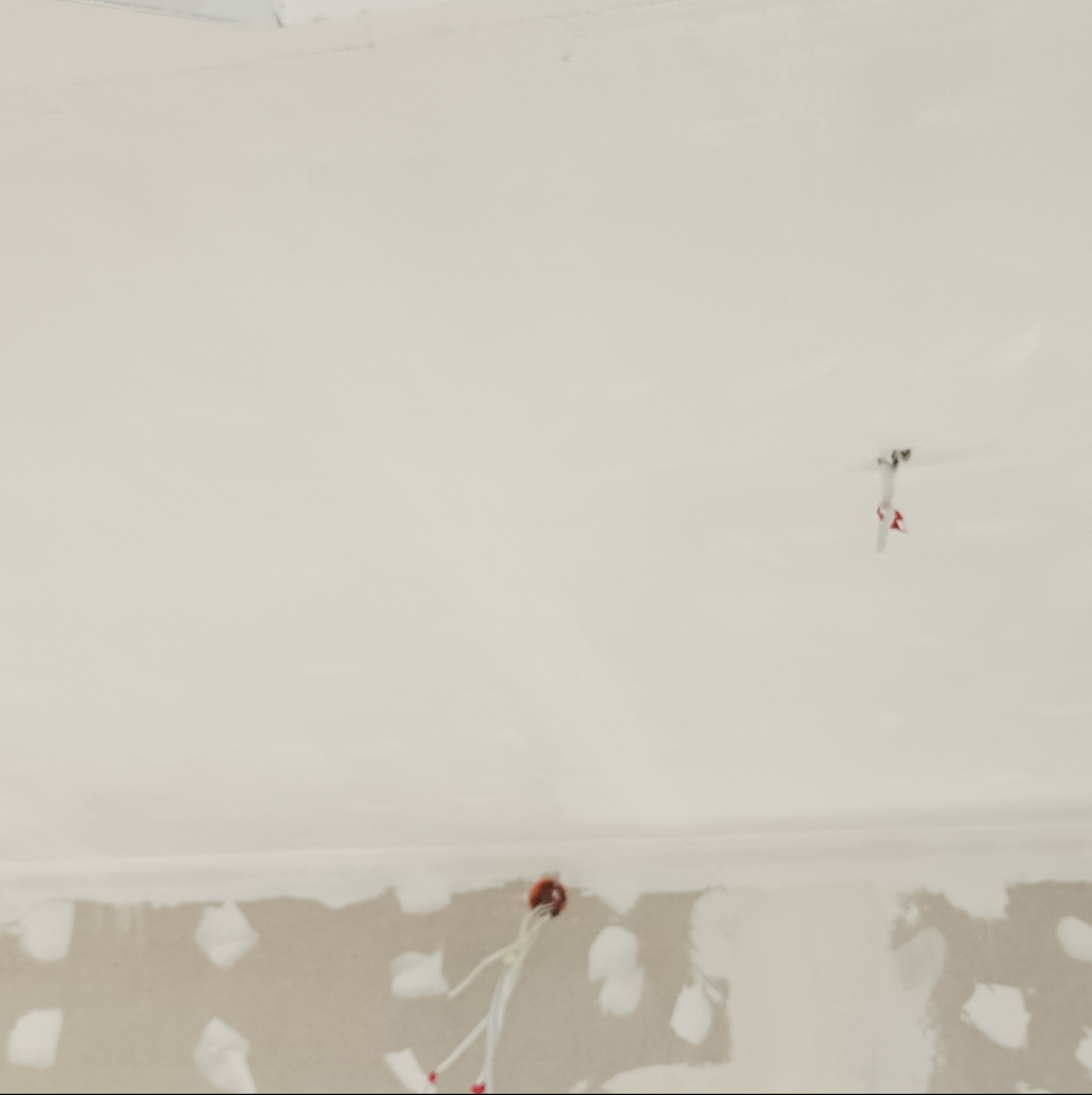 Gładka, biała powierzchnia sufitu po szpachlowaniu, z widocznymi wystającymi przewodami oświetleniowymi i niedoskonałościami na ścianie.