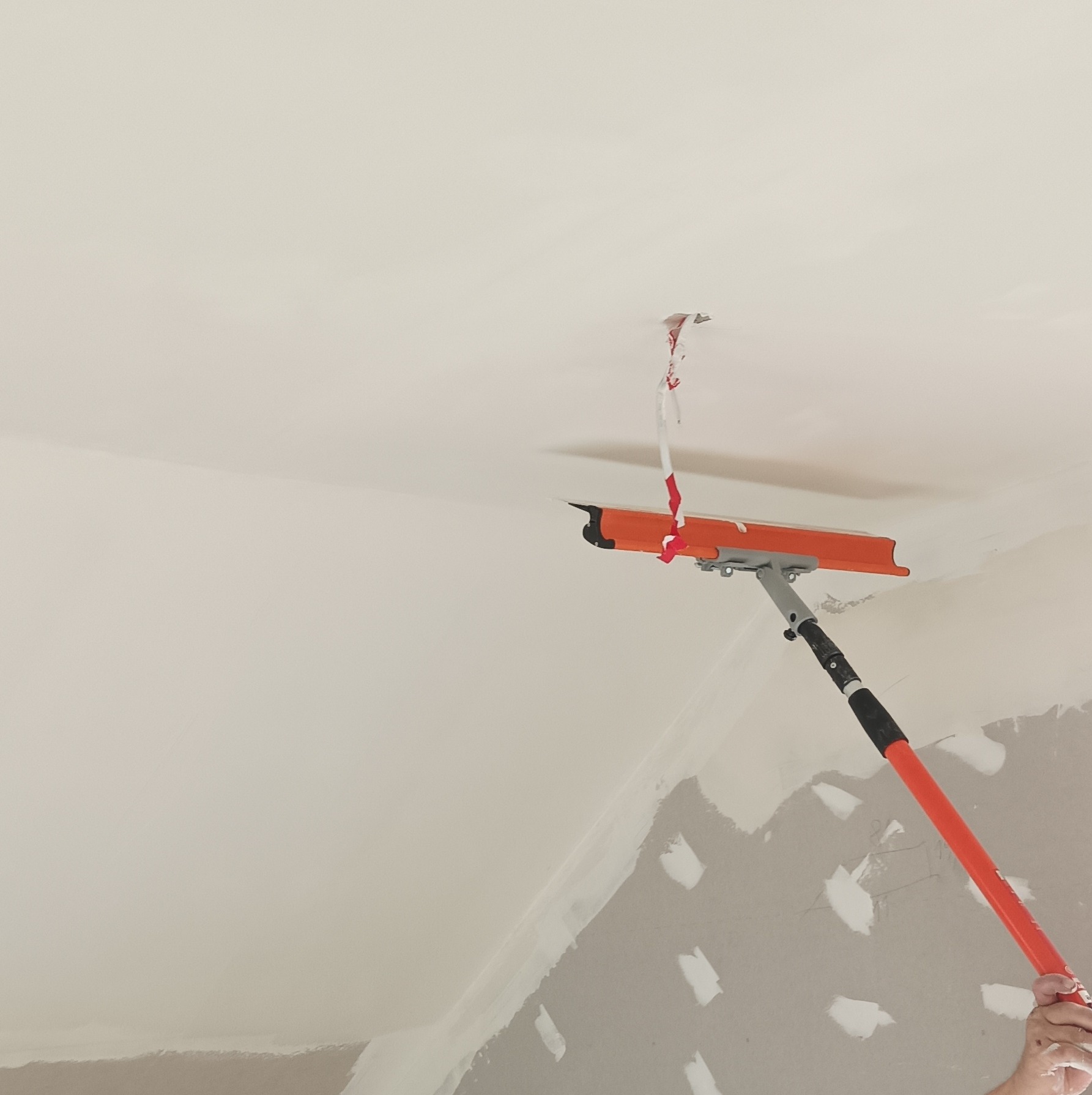 Sufit po szpachlowaniu w Zamościu. Widoczna szpachla na łączeniach płyt gipsowych i narzędzie do rozprowadzania masy. Praca w toku.