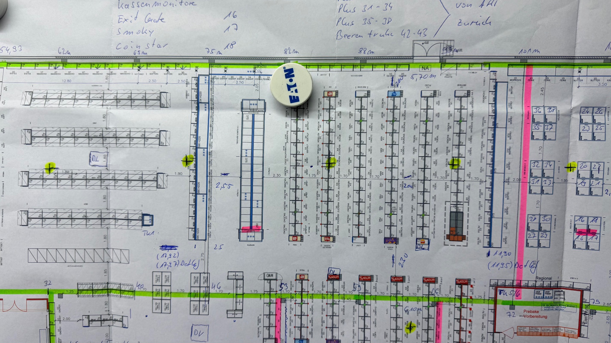 Plan rozkładu towarów w sklepie z naklejonym logo Eaton, widok z góry. Ręcznie naniesione notatki i oznaczenia kolorami na papierze formatu A3.