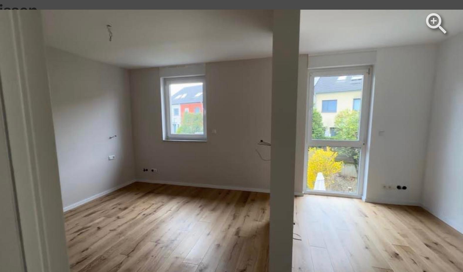 Jasne wnętrze po remoncie w Zarszynie: ułożone panele podłogowe, gładkie ściany, okno i drzwi balkonowe z widokiem na zieleń. Minimalistyczny design, gotowe do zamieszkania.