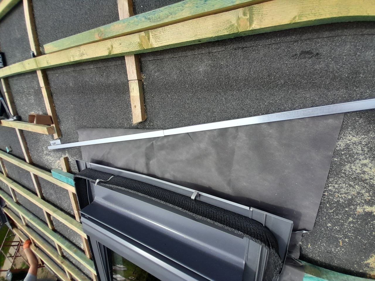 Detal dachu w trakcie budowy: widoczne drewniane elementy konstrukcyjne, membrana dachowa i fragment systemu odprowadzania wody. Perspektywa z góry.