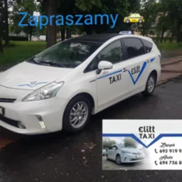 Biała taksówka hybrydowa marki Toyota z niebieskimi akcentami i logo 'Elitt Taxi' na zewnątrz, zaparkowana na mokrej ulicy. Wizytówka firmy z danymi kontaktowymi.