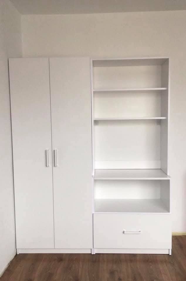 Biała szafa z półkami i szufladą, minimalistyczny design, drewniana podłoga. Gotowa zabudowa meblowa w jasnym wnętrzu.