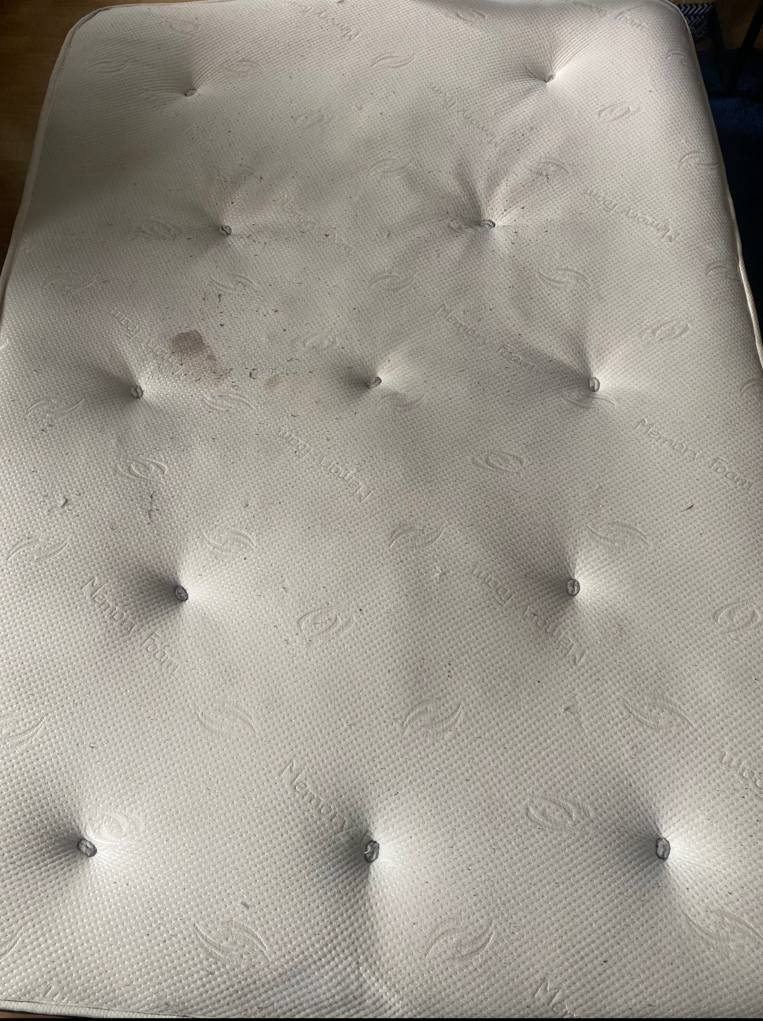 Zabrudzony materac z plamą i drobnymi zanieczyszczeniami, wymagający odświeżenia. Usługi czyszczenia materacy w Szczecinie.