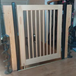 Drewniana barierka schodowa z pionowymi szczebelkami, zamontowana na podeście z paneli. Widoczne metalowe elementy mocujące i fragment balustrady.