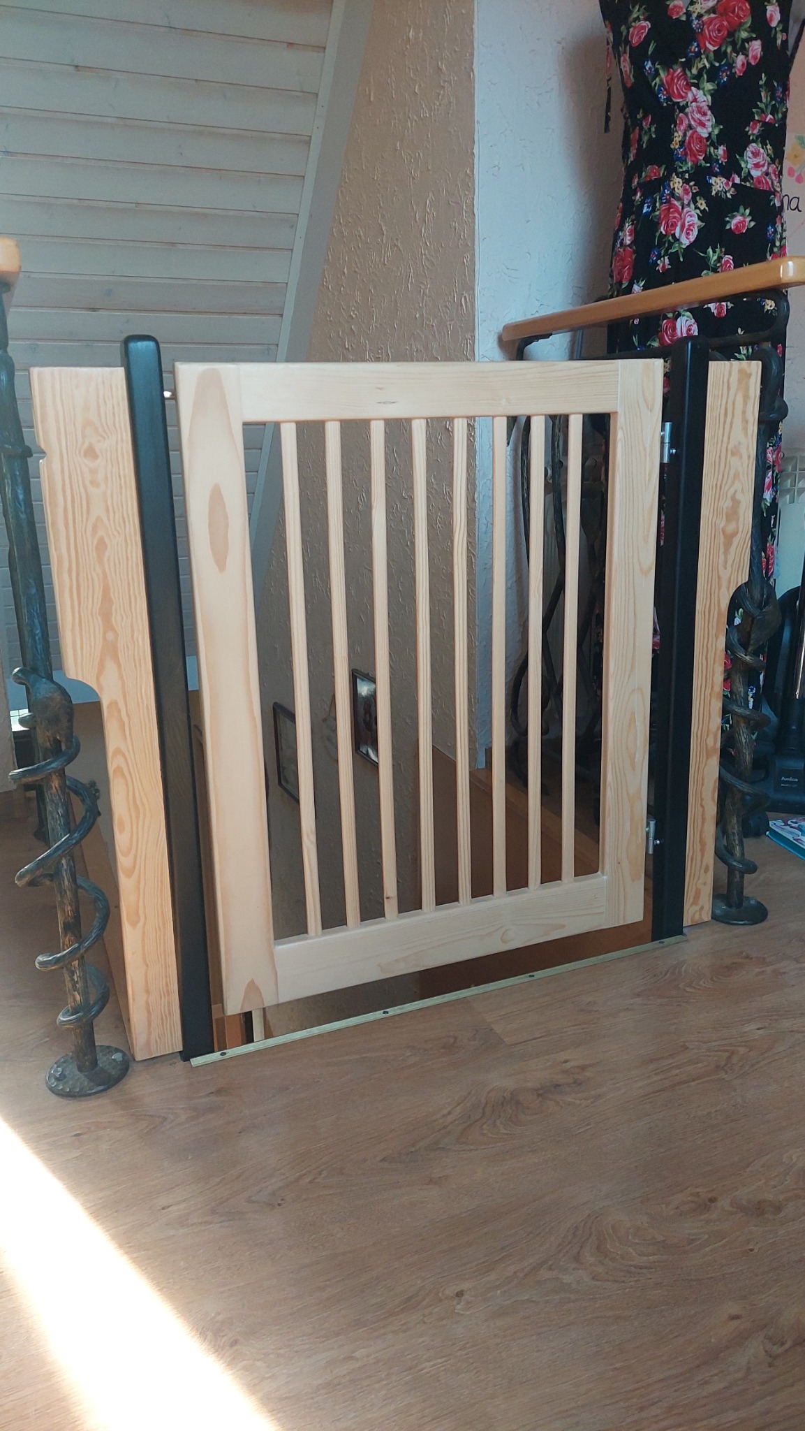 Drewniana barierka schodowa z pionowymi szczebelkami, zamontowana na podeście z paneli. Widoczne metalowe elementy mocujące i fragment balustrady.