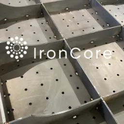 Metalowa konstrukcja kratowa ze spawami i otworami, widok z góry pod kątem. Element konstrukcyjny z logo firmy w lewym górnym rogu.