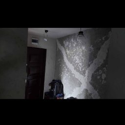 Michał Jankowski - Pokój w trakcie przygotowań do malowania. Ściany z widocznymi śladami po usuniętej starej farbie. Widoczne kable od oświetlenia sufitowego.