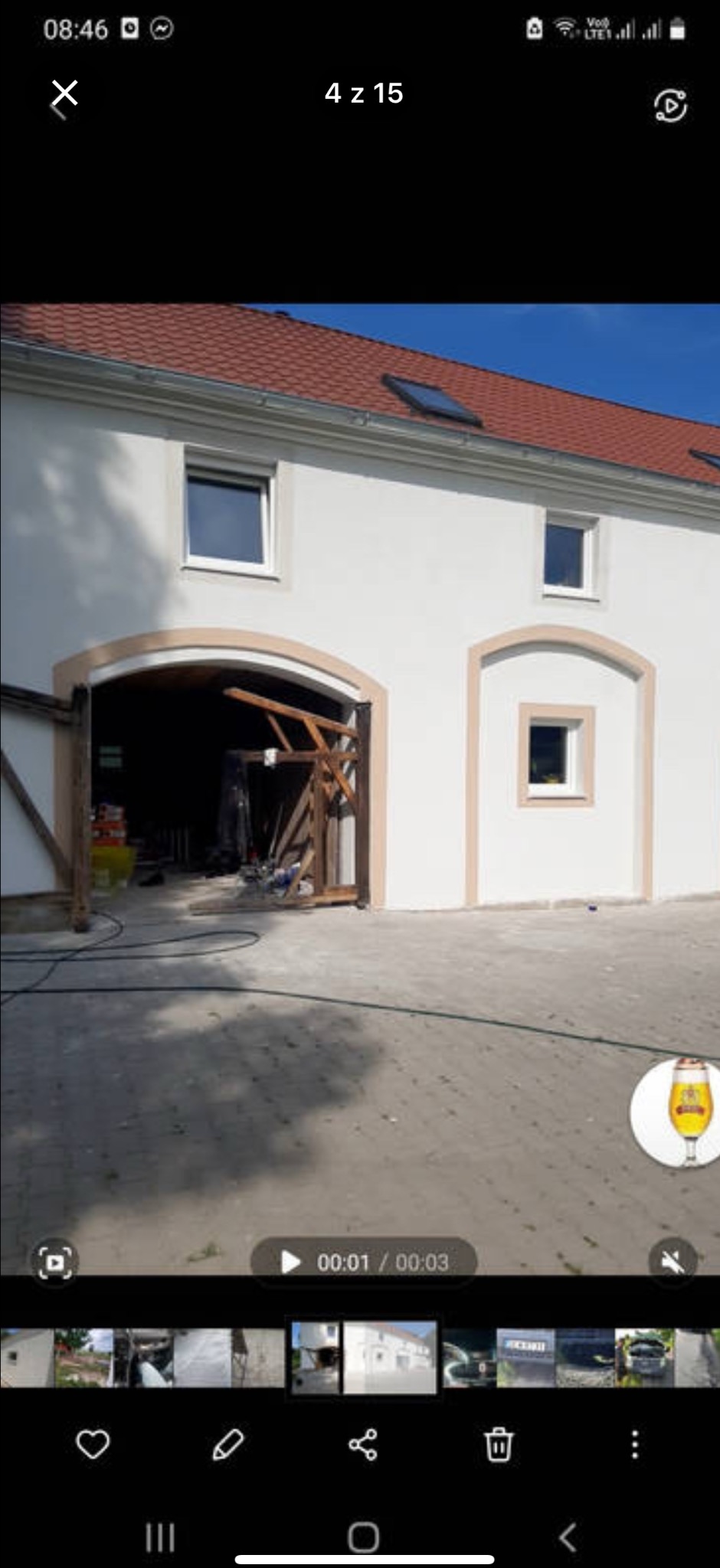 Biały budynek z czerwoną dachówką po remoncie, z beżowymi obramowaniami okien i bramy. Częściowo otwarte wrota garażowe ukazują wnętrze.