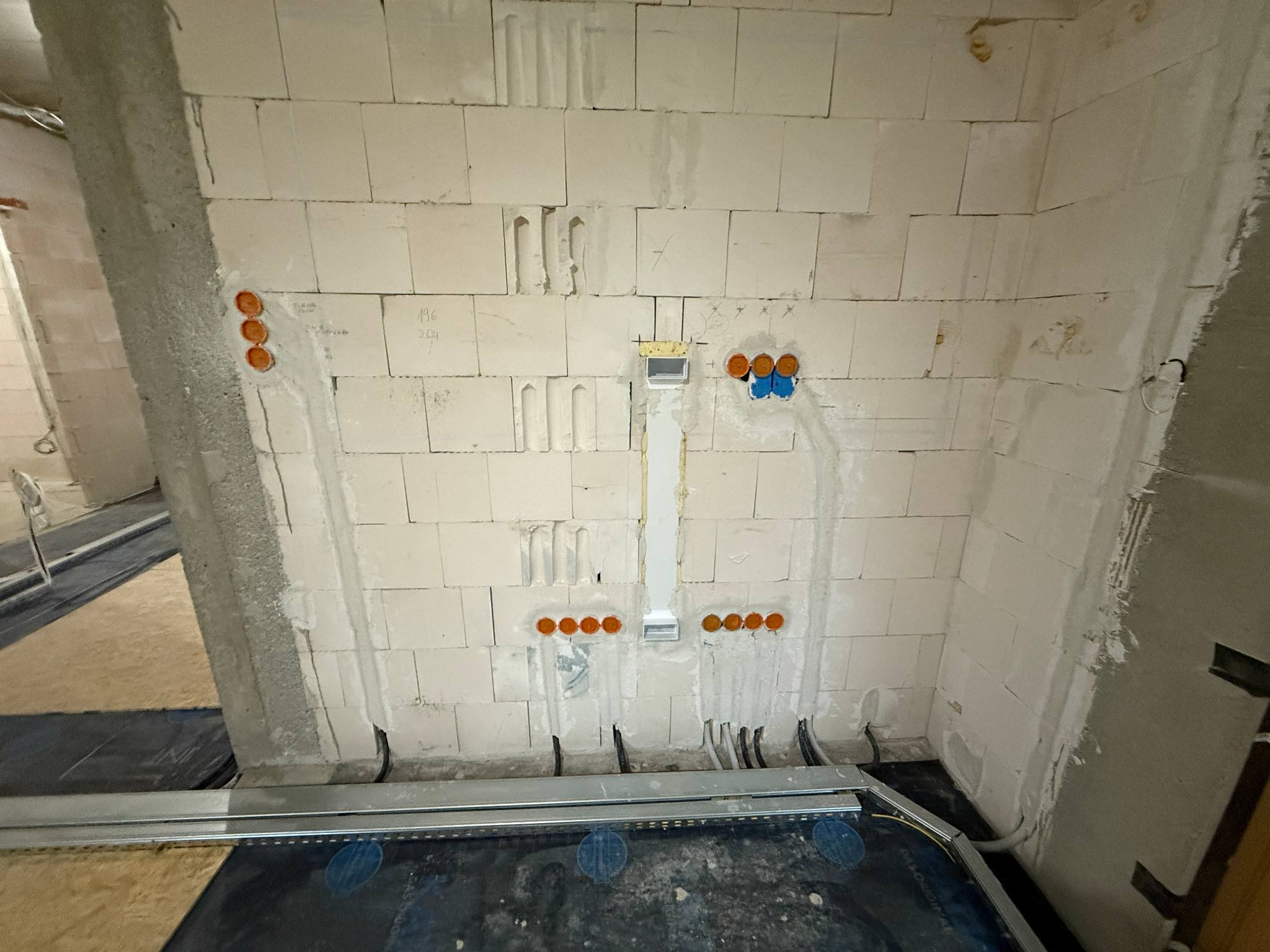 Okablowanie pod inteligentny dom w surowym wnętrzu: widoczne puszki instalacyjne w ścianie z betonu komórkowego i kable. Etap prac instalacyjnych.