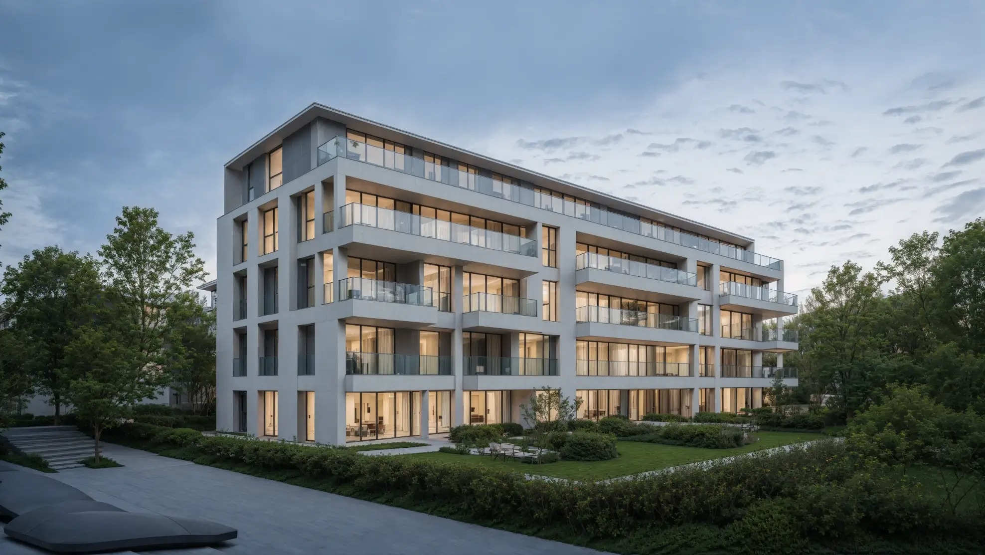 Elegancki, wielopiętrowy apartamentowiec z balkonami i dużymi oknami, otoczony zielenią w spokojnej okolicy. Nowoczesna architektura i subtelne oświetlenie budynku.