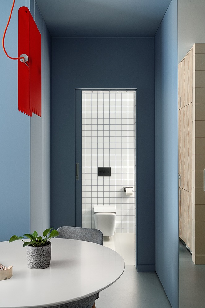 Nowoczesna aranżacja wnętrza z widokiem na łazienkę w Bydgoszczy. Minimalistyczny design, białe płytki i toaleta. Elementy dekoracyjne: roślina, lampa.