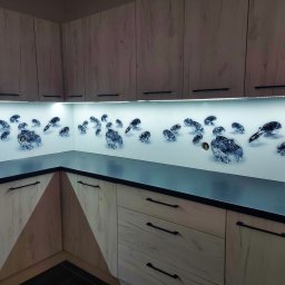 M-K Studio - Szklany panel kuchenny z motywem diamentów, zamontowany między szafkami a blatem. Białe tło, czarne blaty, drewnopodobne fronty szafek.