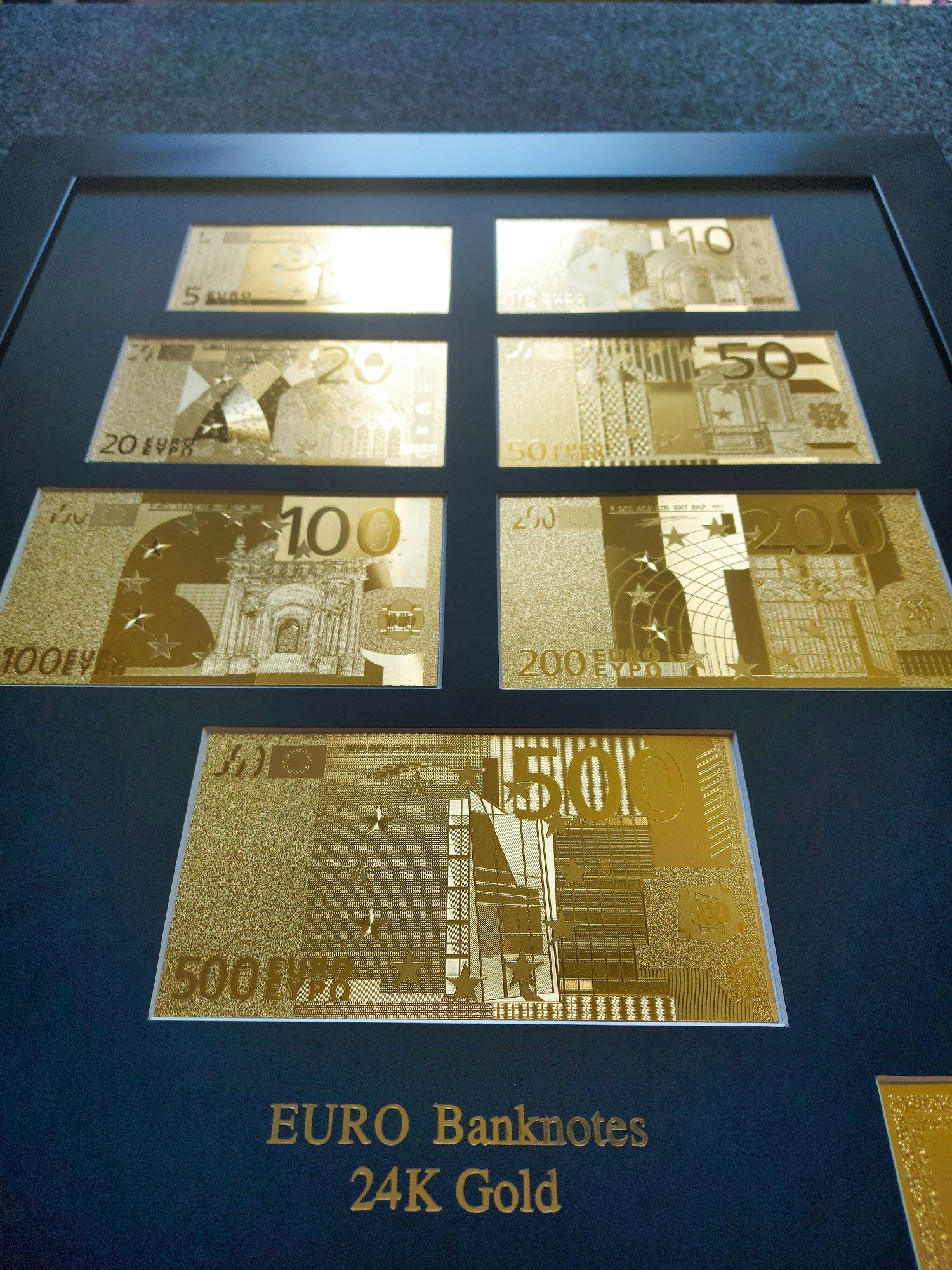 Kolekcja złotych banknotów euro w ramce, prezentująca nominały od 5 do 500 euro. Metaliczny połysk i precyzyjne detale podkreślają unikalny charakter.
