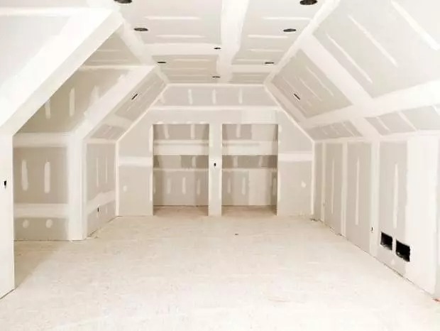 Poddasze po montażu płyt kartonowo-gipsowych z widocznymi spoinami, przygotowane do dalszych prac wykończeniowych. Skosy dachu i wnęki szaf.