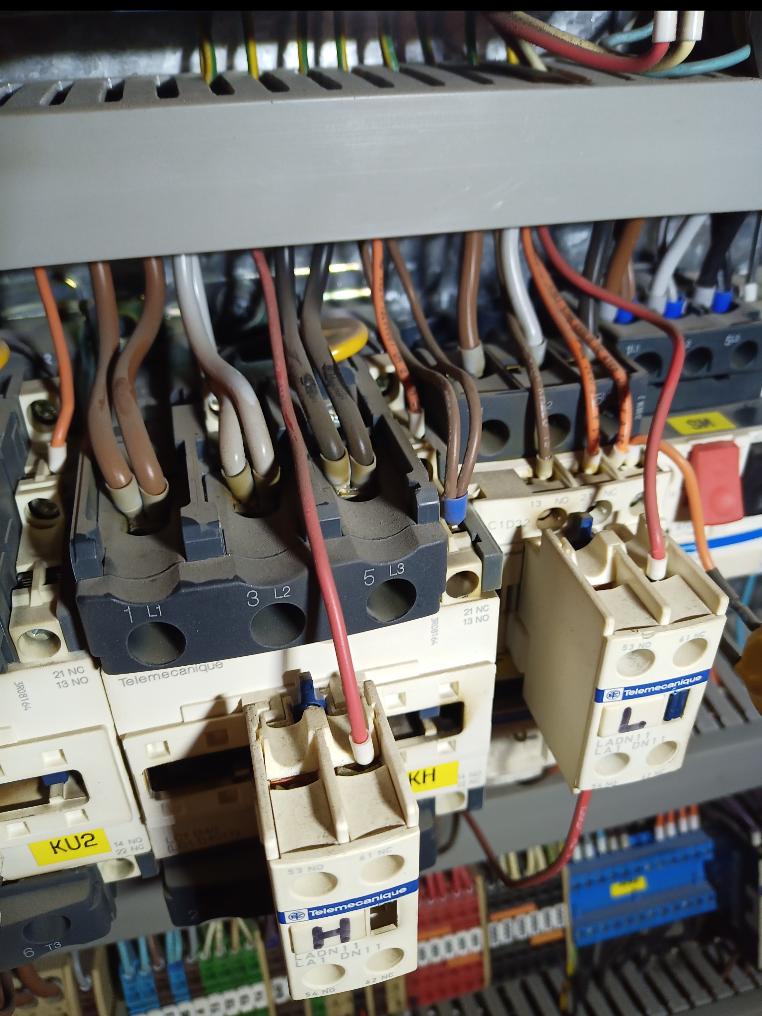 Szczegółowe ujęcie wnętrza rozdzielnicy elektrycznej z widocznymi przewodami, stycznikami i elementami sterowniczymi. Widoczne oznaczenia Telemecanique.