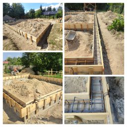 TUBUD TOMASZ URZĘDOWICZ - Szeroki kadr na szalunek fundamentów zbrojonych stalą, wypełnionych piaskiem. Widoczne drewniane deski, zbrojenie i piasek. Prace ziemne w toku, teren budowy.